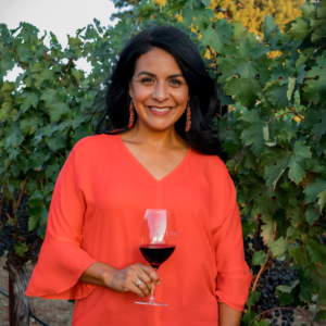 Monica Lopez in a vineyard holding a glass of red wine